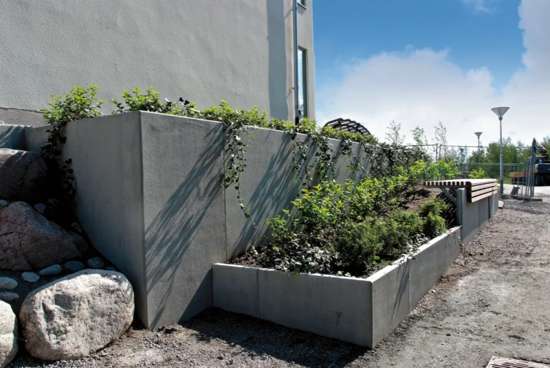 Planting beds made from tongue and groove L-walls by a house wall