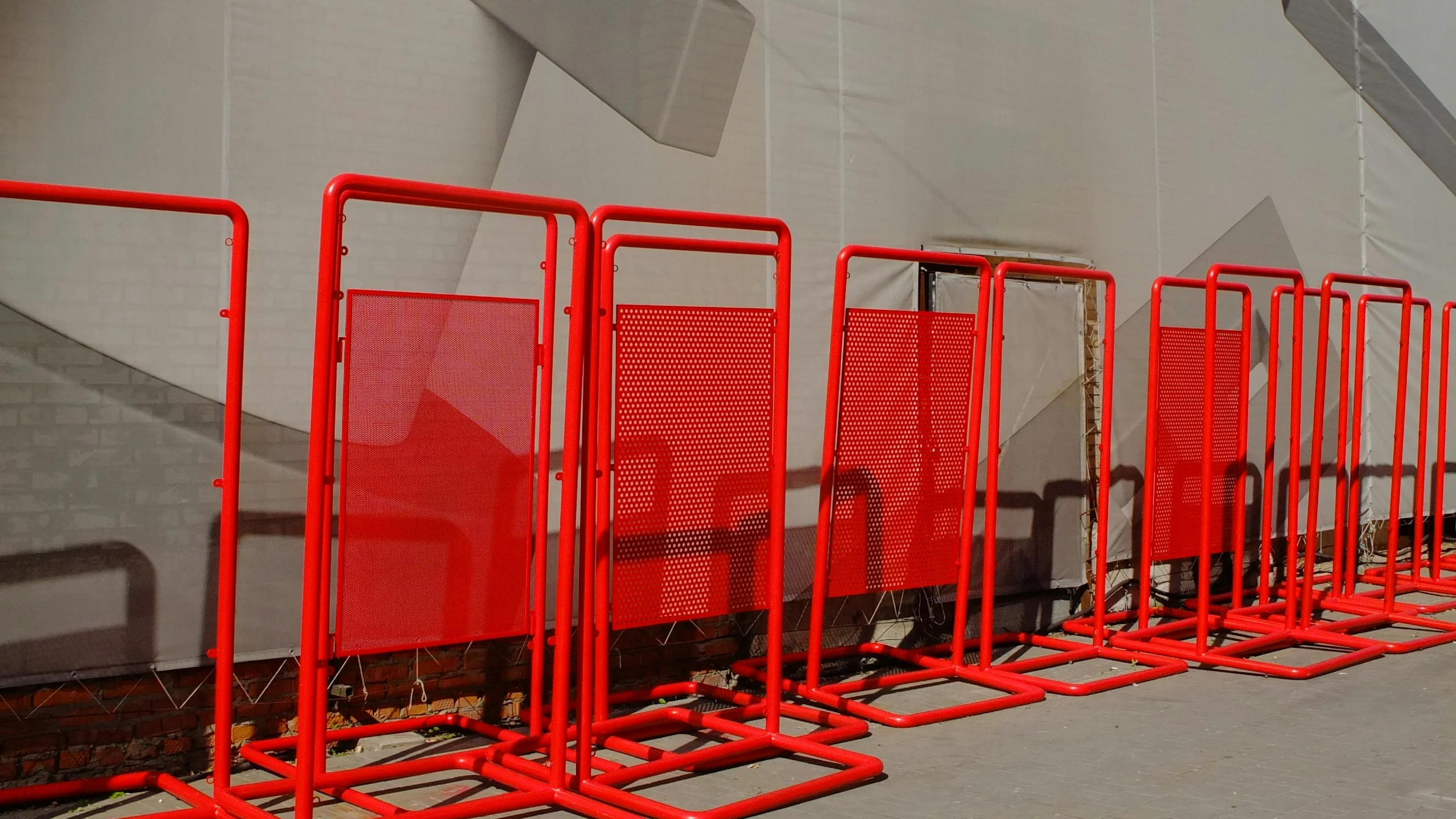 Row of red metal crowd-control barriers on a paved surface