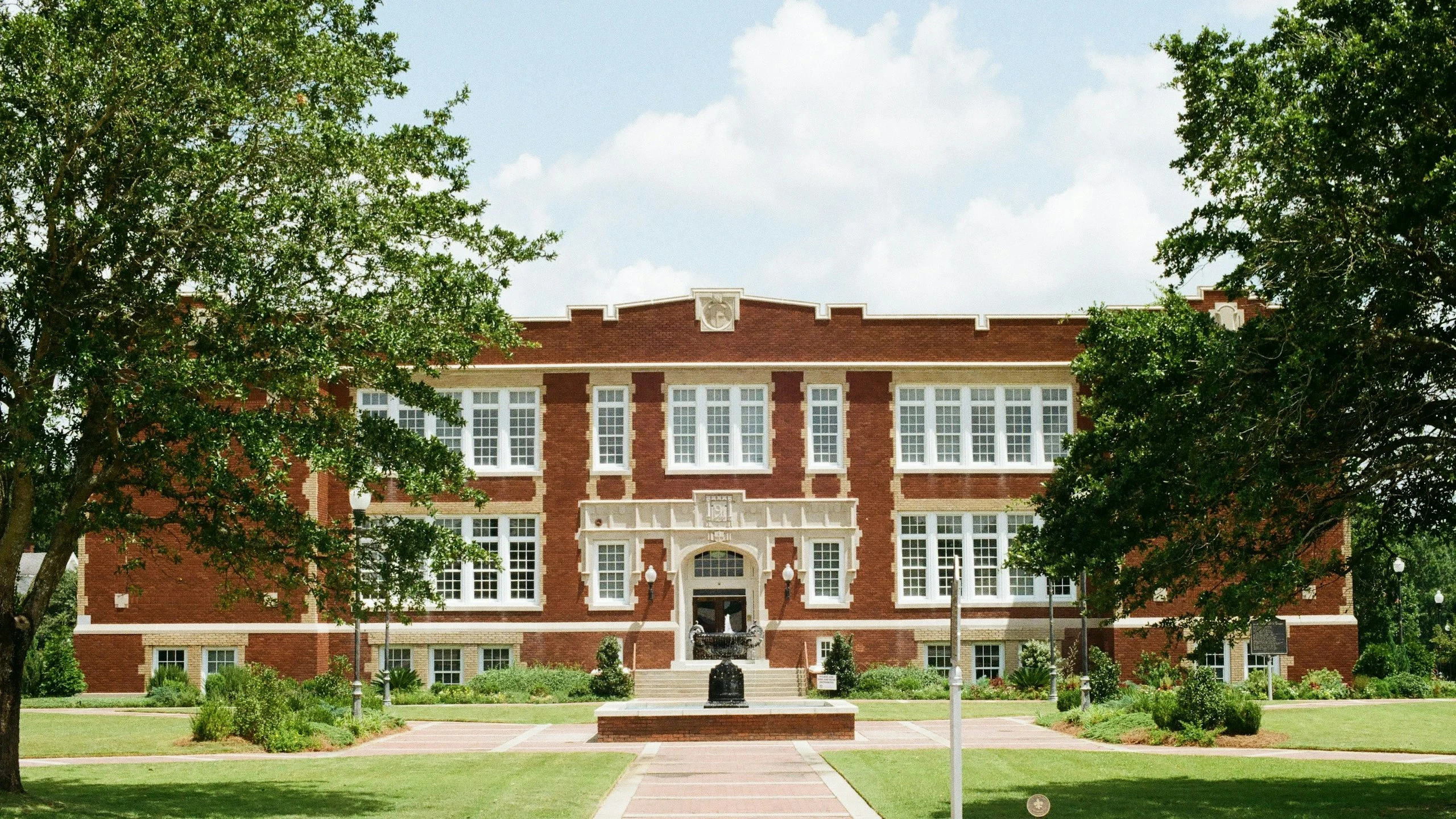 Red-brick school building with trees and a lawn in front